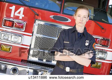 Stock Photograph - Firewoman standing in front of fire engine. Fotosearch