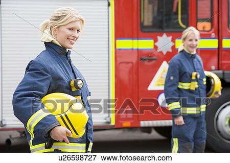 Firewomen standing by fire engine with another firewoman in background (selective focus) View Large Photo Image Stock Photo - Firewomen standing by fire engine with another firewoman in background (selective focus). Fotosearch