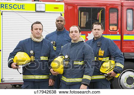 Stock Photo - Four firefighters standing by fire engine. Fotosearch