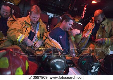 Stock Photo - Four firemen in fire engine putting on gear (blur). Fotosearch
