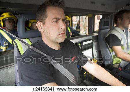Stock Image - Group of firefighters in fire engine with focus on passenger seat (selective focus). Fotosearch