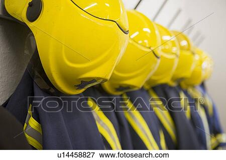 Stock Photo - Line of firefighting uniforms hanging neatly on wall hooks (depth of field). Fotosearch