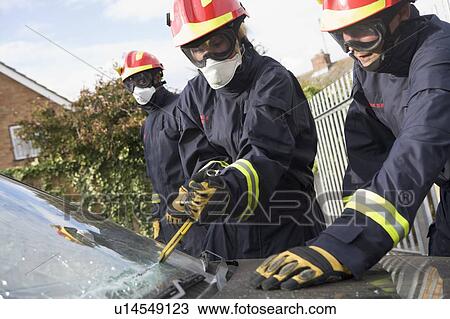 Two firefighters cutting out a windshield after an accident with another firefighter in background View Large Photo Image Stock Image - Two firefighters cutting out a windshield after an accident with another firefighter in background. Fotosearch
