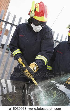 Two firefighters cutting out a windshield after an accident View Large Photo Image Stock Photo - Two firefighters cutting out a windshield after an accident. Fotosearch