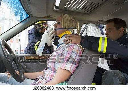 Two firemen helping a woman in neck brace breathe with oxygen mask View Large Photo Image Stock Image - Two firemen helping a woman in neck brace breathe with oxygen mask. Fotosearch