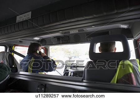 Stock Photo - Two firemen in fire engine with one on the radio. Fotosearch