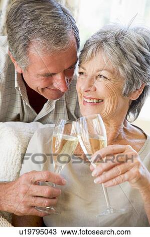 Couple in living room toasting champagne and smiling View Large Photo Image Stock Image - Couple in living room toasting champagne and smiling. Fotosearch
