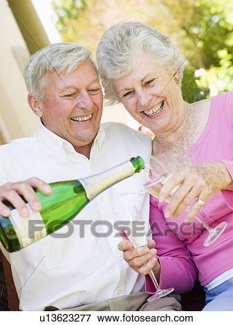 Stock Photo - Couple on patio drinking champagne and smiling. Fotosearch