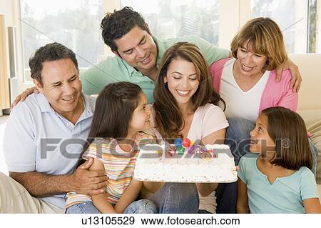Stock Photo - Family in living room with cake smiling. Fotosearch