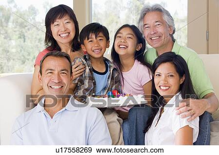 Stock Photo - Family in living room with cake smiling. Fotosearch