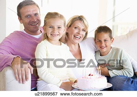 Stock Photo - Family in living room with cake smiling. Fotosearch