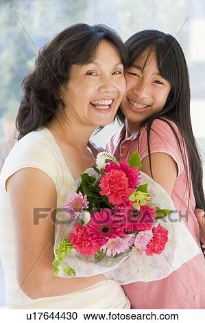 Granddaughter and grandmother holding flowers and smiling View Large Photo Image Stock Image - Granddaughter and grandmother holding flowers and smiling. Fotosearch