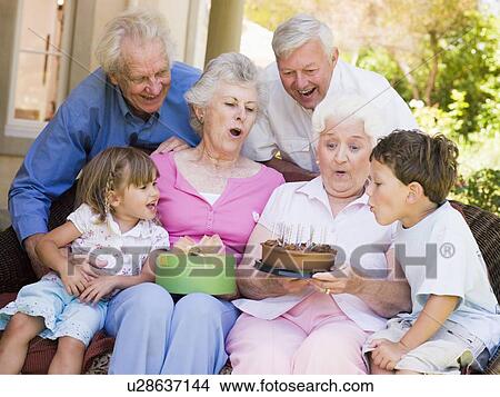 Picture - Grandparents and grandchildren on patio with cake and gift smiling. Fotosearch