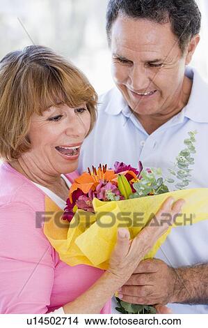 Husband and wife holding flowers and smiling View Large Photo Image Picture - Husband and wife holding flowers and smiling. Fotosearch