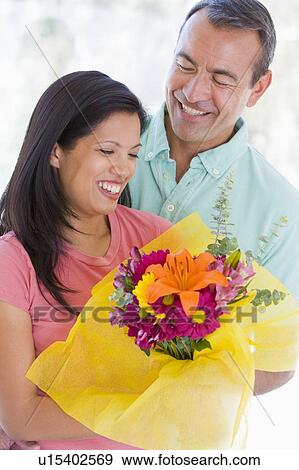 Stock Photo - Husband and wife holding flowers and smiling. Fotosearch