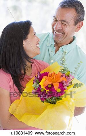 Stock Photo - Husband and wife holding flowers and smiling. Fotosearch