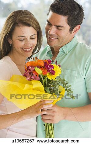 Husband giving wife flowers and smiling View Large Photo Image Stock Photo - Husband giving wife flowers and smiling. Fotosearch