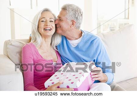 Husband giving wife gift in living room kissing her and smiling View Large Photo Image Stock Photography - Husband giving wife gift in living room kissing her and smiling. Fotosearch