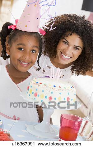 Stock Image - Mother and daughter with birthday cake smiling. Fotosearch