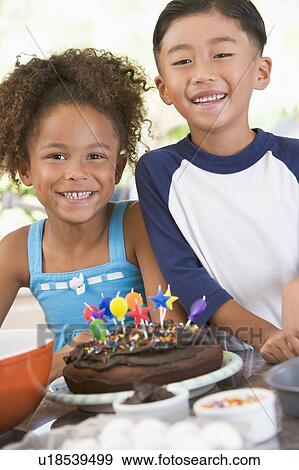 Two children in kitchen with birthday cake smiling View Large Photo Image Stock Photo - Two children in kitchen with birthday cake smiling. Fotosearch