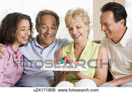 Stock Photograph - Two couples in living room with cake smiling. Fotosearch