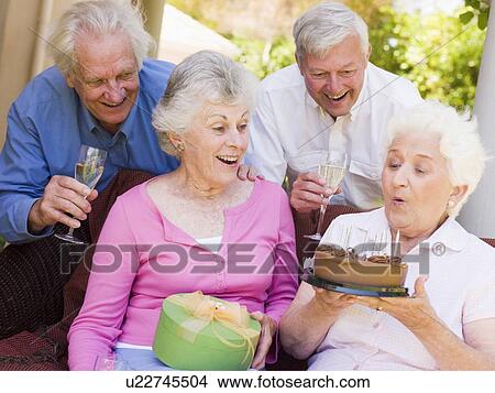 Picture - Two couples on patio with cake and gift smiling. Fotosearch
