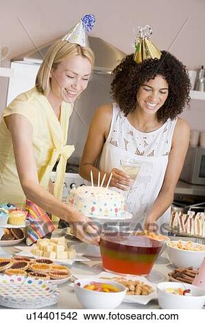 Two women at party setting out food smiling View Large Photo Image Stock Image - Two women at party setting out food smiling. Fotosearch