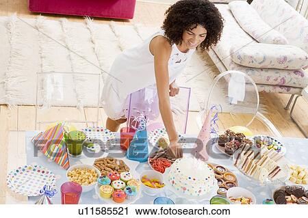 Woman at party fixing cake on food table smiling View Large Photo Image Stock Image - Woman at party fixing cake on food table smiling. Fotosearch