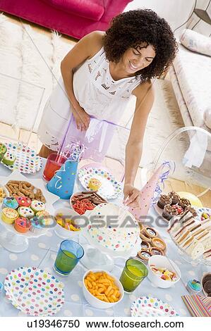Woman at party putting candles in cake on food table smiling View Large Photo Image Stock Image - Woman at party putting candles in cake on food table smiling. Fotosearch