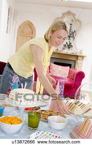 Stock Photograph - Woman at party setting out food and smiling. Fotosearch