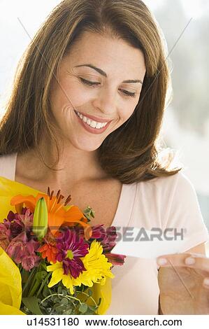 Woman holding flowers and reading note smiling View Large Photo Image Stock Image - Woman holding flowers and reading note smiling. Fotosearch