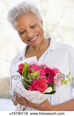 Stock Photo - Woman holding flowers and smiling. Fotosearch