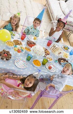 Young children at party sitting at table with food smiling View Large Photo Image Stock Photo - Young children at party sitting at table with food smiling. Fotosearch