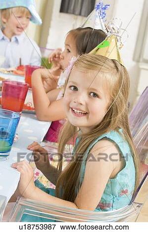 Stock Photo - Young girl at party sitting at table with food smiling. Fotosearch