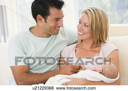 Stock Photo - Couple in living room with baby smiling. Fotosearch