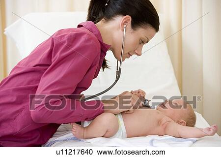 Stock Image - Doctor giving checkup with stethoscope to baby in exam room. Fotosearch