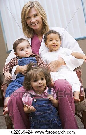 Picture - Doctor sitting with three IVF children smiling. Fotosearch