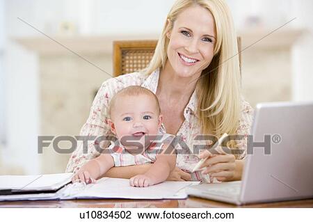 Mother and baby in dining room with laptop smiling View Large Photo Image Stock Image - Mother and baby in dining room with laptop smiling. Fotosearch