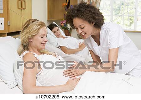 Stock Photograph - Nurse checking pregnant woman's belly and smiling. Fotosearch
