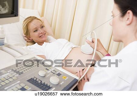 Pregnant woman getting ultrasound from doctor View Large Photo Image Stock Photo - Pregnant woman getting ultrasound from doctor. Fotosearch