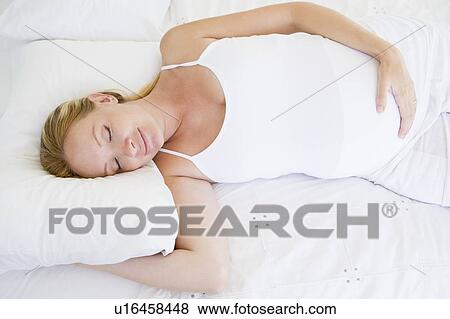 Stock Photo - Pregnant woman lying in bed sleeping. Fotosearch