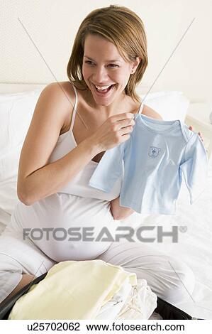 Pregnant woman packing baby clothing in suitcase smiling View Large Photo Image Stock Image - Pregnant woman packing baby clothing in suitcase smiling. Fotosearch