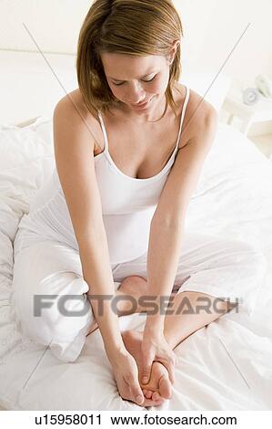 Pregnant woman sitting in bed smiling and rubbing feet View Large Photo Image Stock Image - Pregnant woman sitting in bed smiling and rubbing feet. Fotosearch