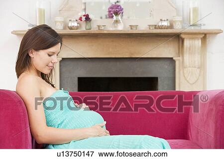 Pregnant woman sitting in living room smiling View Large Photo Image Stock Photo - Pregnant woman sitting in living room smiling. Fotosearch