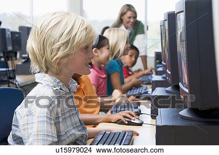 Children at computer terminals with teacher in background (depth of field/high key) View Large Photo Image Picture - Children at computer terminals with teacher in background (depth of field/high key). Fotosearch