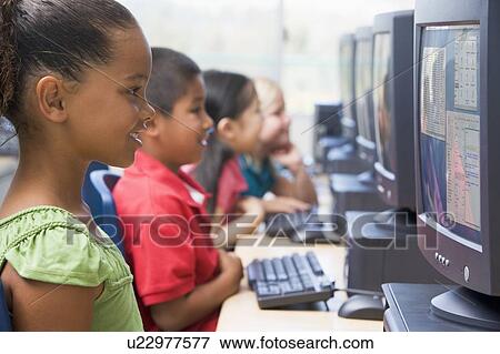 Stock Photo - Four children at computer terminals (depth of focus/high key). Fotosearch