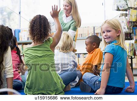 Student in class looking at camera with teacher reading in background (selective focus) View Large Photo Image Stock Photograph - Student in class looking at camera with teacher reading in background (selective focus). Fotosearch