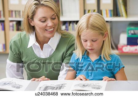 Stock Photo - Student in class reading with teacher. Fotosearch