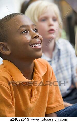Stock Image - Students in class sitting on floor paying attention (selective focus). Fotosearch