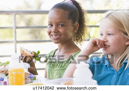Stock Image - Students outdoors eating lunch (selective focus). Fotosearch